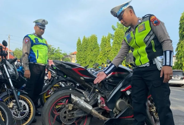 aparat kepolisian menunjukkan knalpot brong di salah satu motor hasil patroli selama dua hari (Foto: ANTARA)