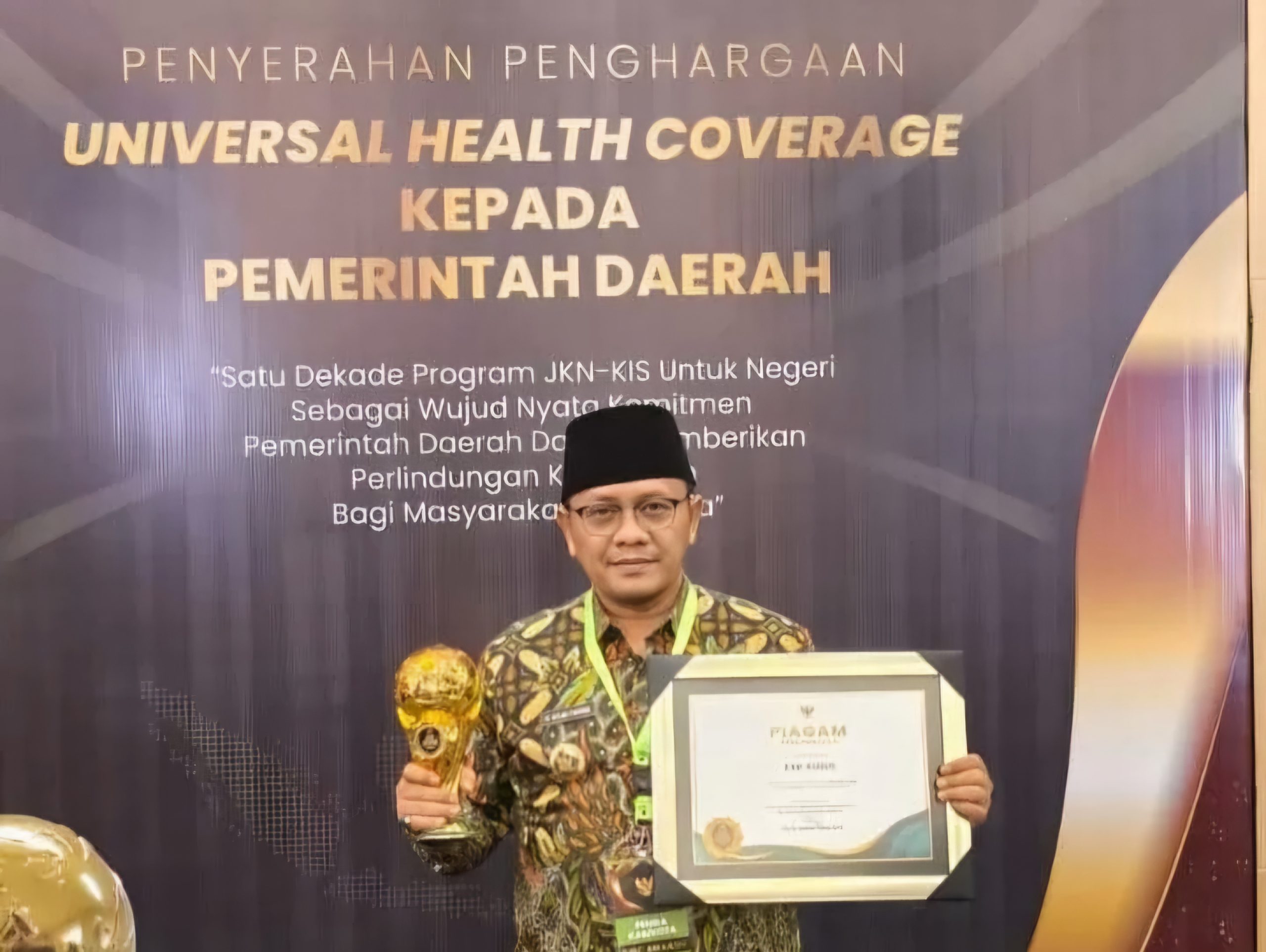 Pj Bupati Kudus Hasan Chabibie menerimakan penghargaan UHC Award 2024 (foto: Radar Kudus)