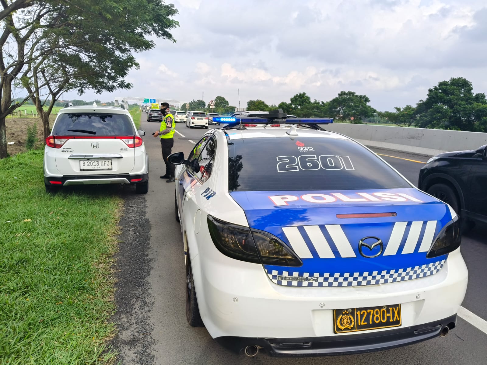 Aparat kepolisian menegur pemudik yang ketahuan berhenti di bahu jalan tol.