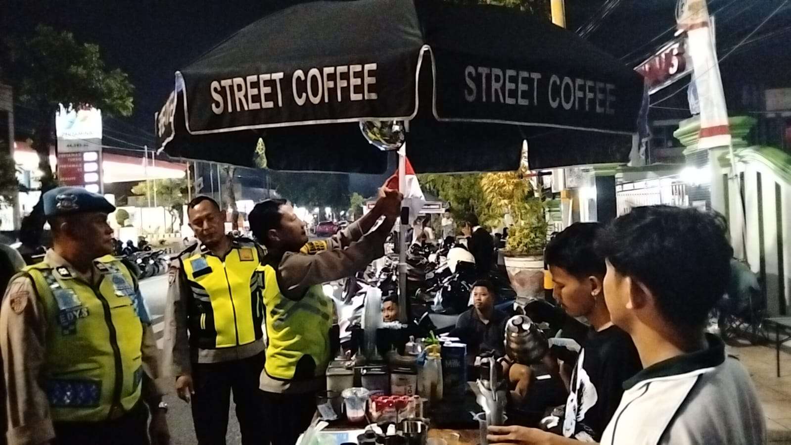 Polsek Kudus Kota dipimpin Kapolsek AKP Subkhan membagikan bendera merah putih kepada PKL Zona 1 di sepanjang Jalan Jenderal Sudirman malam ini Senin (04/08/2025).