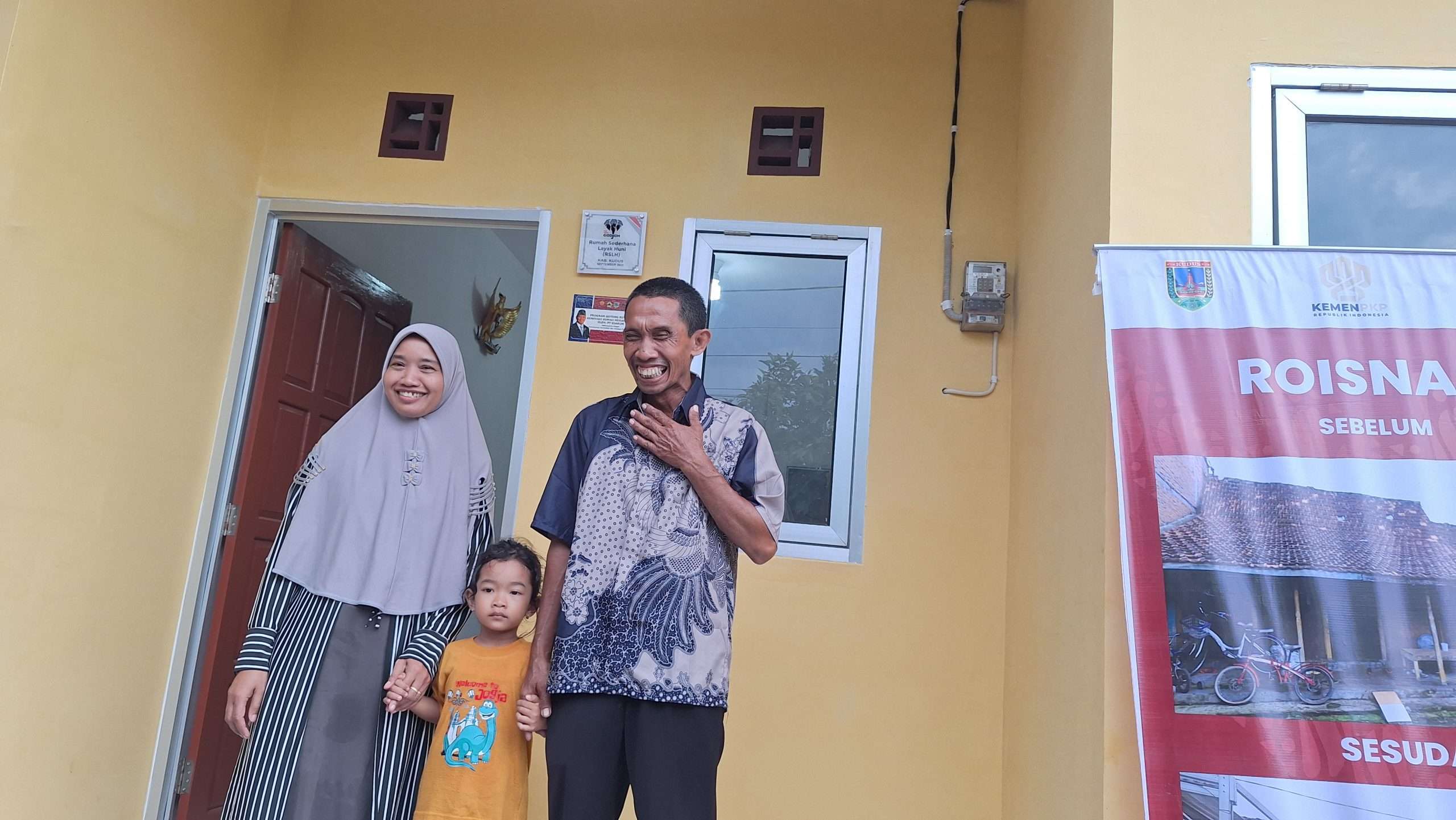 Roisnan, warga Desa Pasuruan Kidul, Kecamatan Jati, Kabupaten Kudus bersama keluarganya berfoto di depan rumah barunya